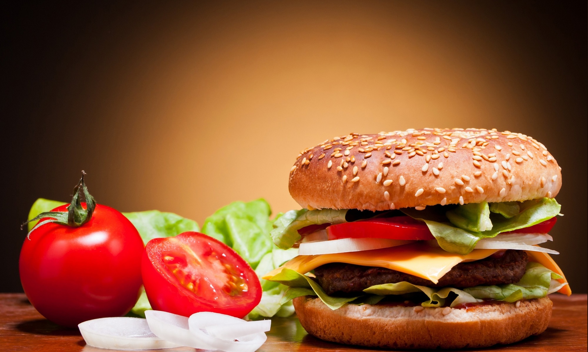 American hamburger on a wooden plate with tomatos.