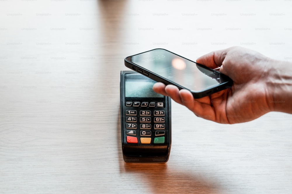 a person holding a cell phone on top of a wooden table - innovation